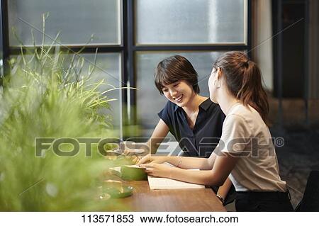 Stock Image - Young girlfriends at a cafe. Fotosearch