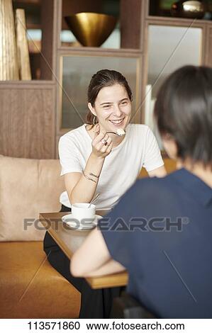 Stock Image - Young girlfriends at a cafe. Fotosearch
