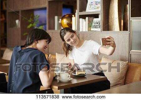 Young girlfriends at a cafe View Large Photo Image Stock Photo - Young girlfriends at a cafe. Fotosearch