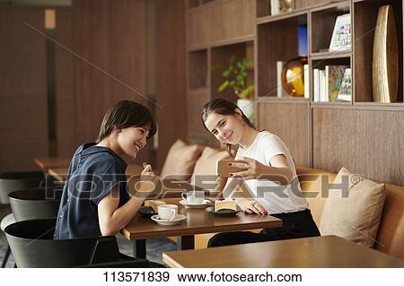 Young girlfriends at a cafe View Large Photo Image Stock Photo - Young girlfriends at a cafe. Fotosearch