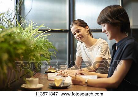 Stock Photo - Young girlfriends at a cafe. Fotosearch