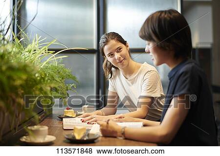 Stock Photo - Young girlfriends at a cafe. Fotosearch