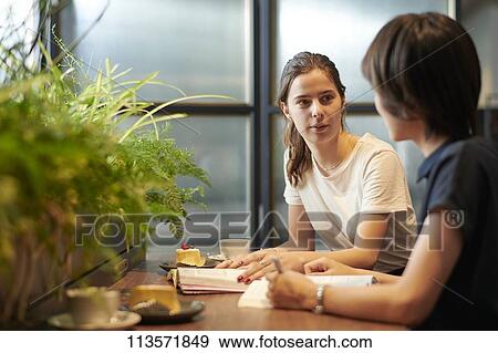 Young girlfriends at a cafe View Large Photo Image Stock Photo - Young girlfriends at a cafe. Fotosearch