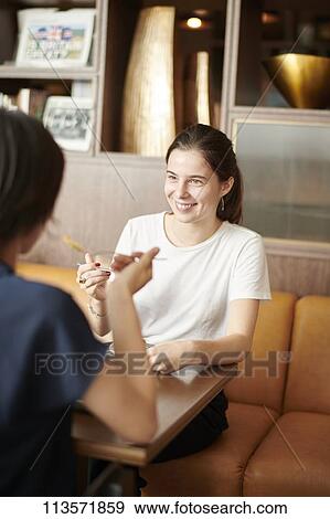 Young girlfriends at a cafe View Large Photo Image Stock Photo - Young girlfriends at a cafe. Fotosearch