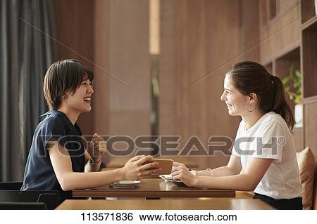 Young girlfriends at a cafe View Large Photo Image Stock Photograph - Young girlfriends at a cafe. Fotosearch
