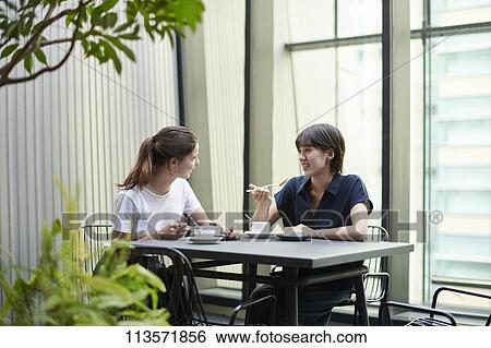 Stock Photograph - Young girlfriends at a cafe. Fotosearch