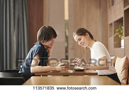 Young girlfriends at a cafe View Large Photo Image Stock Photography - Young girlfriends at a cafe. Fotosearch