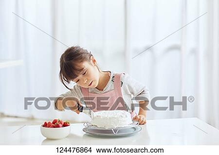 Picture - Young happy girl preparing a cake in the kitchen. Fotosearch
