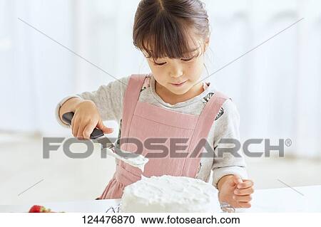 Stock Image - Young happy girl preparing a cake in the kitchen. Fotosearch