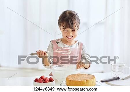 Stock Photo - Young happy girl preparing a cake in the kitchen. Fotosearch
