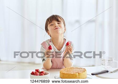Stock Photo - Young happy girl preparing a cake in the kitchen. Fotosearch