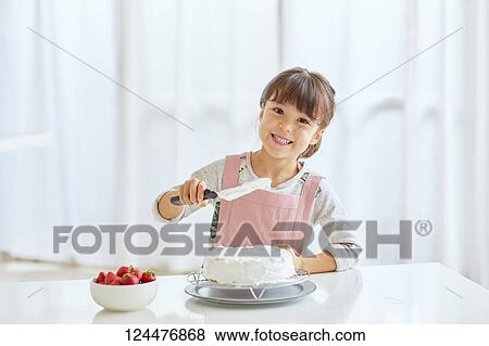 Stock Photo - Young happy girl preparing a cake in the kitchen. Fotosearch