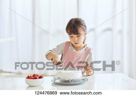 Stock Photo - Young happy girl preparing a cake in the kitchen. Fotosearch