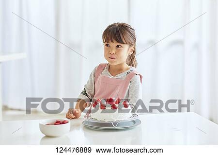 Stock Photo - Young happy girl preparing a cake in the kitchen. Fotosearch