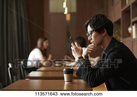 Stock Image - Young Japanese businessman at a cafe. Fotosearch