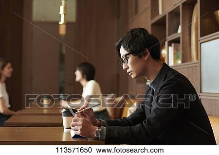 Stock Image - Young Japanese businessman at a cafe. Fotosearch