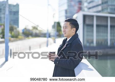 Stock Image - Young Japanese businessman outside. Fotosearch