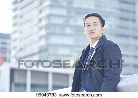 Stock Image - Young Japanese businessman outside. Fotosearch