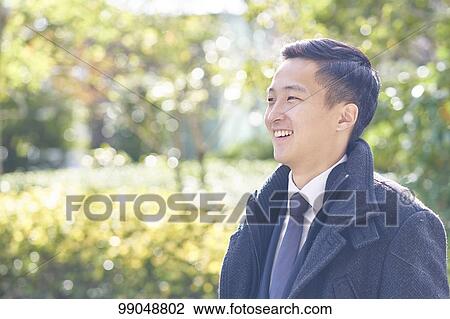 Stock Image - Young Japanese businessman outside. Fotosearch