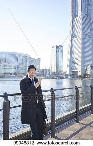Stock Image - Young Japanese businessman outside. Fotosearch