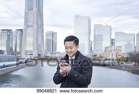 Stock Image - Young Japanese businessman outside. Fotosearch