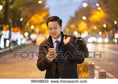 Stock Image - Young Japanese businessman outside. Fotosearch