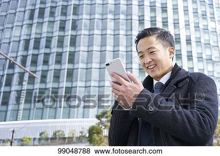 Stock Photo - Young Japanese businessman outside. Fotosearch