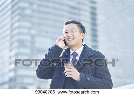 Stock Photograph - Young Japanese businessman outside. Fotosearch