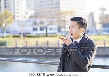 Stock Photograph - Young Japanese businessman outside. Fotosearch