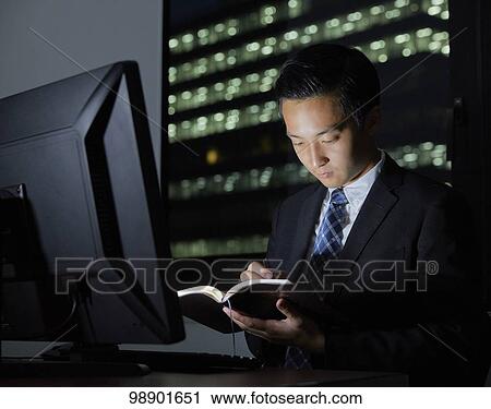 Stock Image - Young Japanese businessman working late at night. Fotosearch