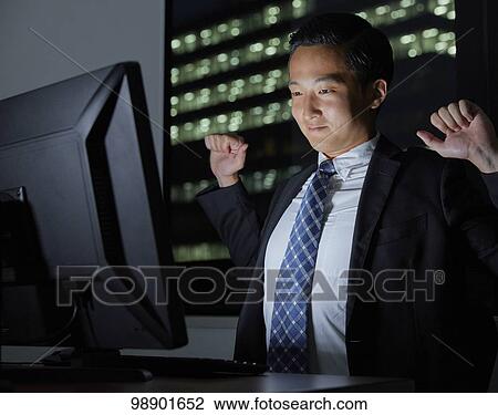 Stock Image - Young Japanese businessman working late at night. Fotosearch