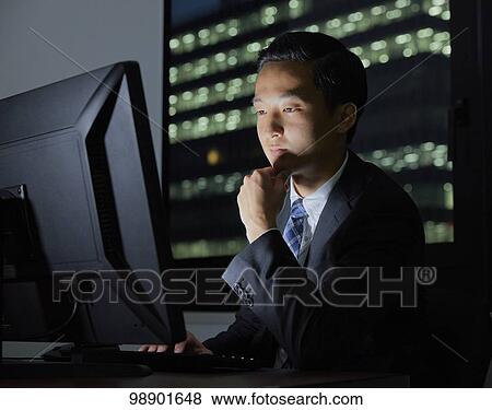 Stock Photo - Young Japanese businessman working late at night. Fotosearch
