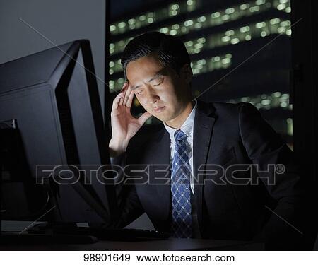Stock Photo - Young Japanese businessman working late at night. Fotosearch