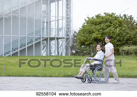 Picture - Young Japanese caregiver taking care of elder patient. Fotosearch