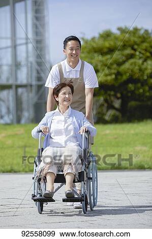 Stock Photo - Young Japanese caregiver taking care of elder patient. Fotosearch