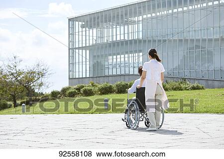 Stock Photo - Young Japanese caregiver taking care of elder patient. Fotosearch