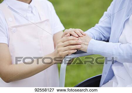 Stock Photo - Young Japanese caregiver taking care of elder patient. Fotosearch