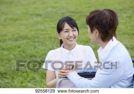 Young Japanese caregiver taking care of elder patient View Large Photo Image Stock Photo - Young Japanese caregiver taking care of elder patient. Fotosearch