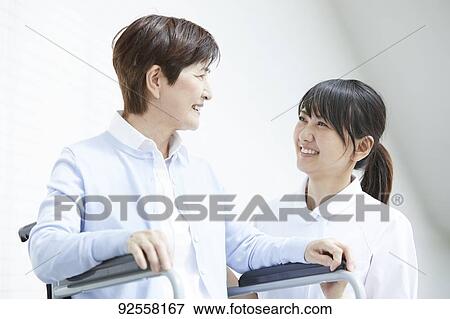 Young Japanese caregiver taking care of elder patient View Large Photo Image Stock Photo - Young Japanese caregiver taking care of elder patient. Fotosearch