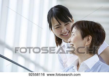 Stock Photograph - Young Japanese caregiver taking care of elder patient. Fotosearch