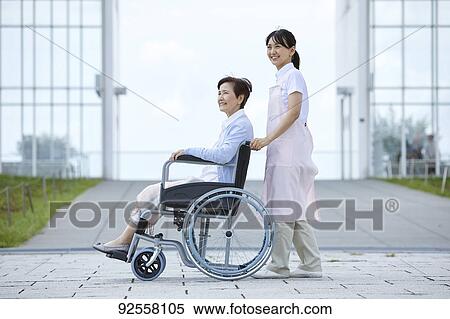 Stock Photography - Young Japanese caregiver taking care of elder patient. Fotosearch