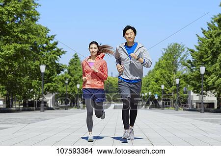 Picture - Young Japanese couple running downtown Tokyo. Fotosearch