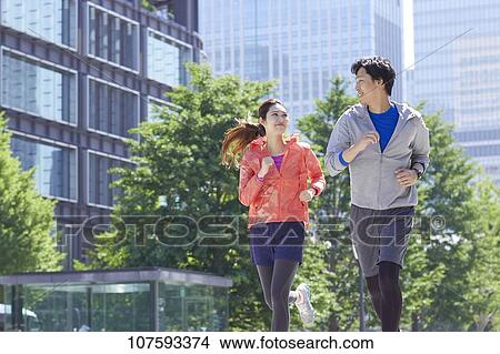 Picture - Young Japanese couple running downtown Tokyo. Fotosearch