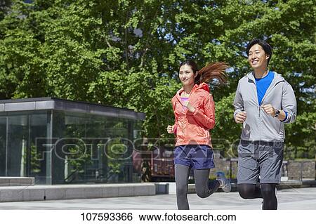 Stock Photograph - Young Japanese couple running downtown Tokyo. Fotosearch