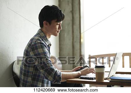 Stock Photo - Young Japanese man at a cafe. Fotosearch
