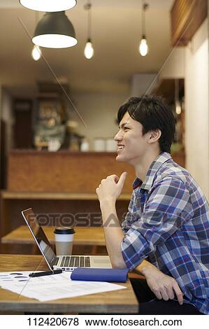 Stock Photo - Young Japanese man at a cafe. Fotosearch