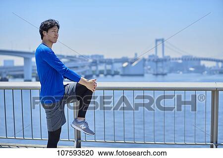 Stock Image - Young Japanese man running downtown Tokyo. Fotosearch