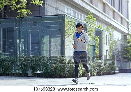 Stock Photo - Young Japanese man running downtown Tokyo. Fotosearch