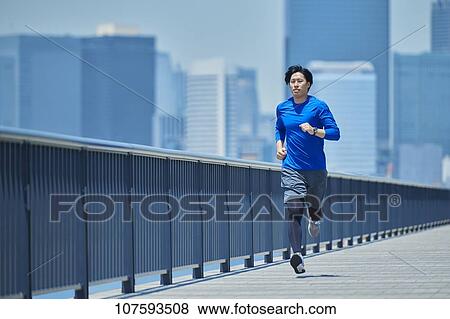 Stock Photo - Young Japanese man running downtown Tokyo. Fotosearch
