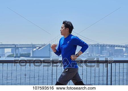 Stock Photograph - Young Japanese man running downtown Tokyo. Fotosearch